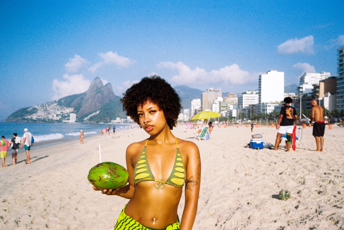 Woman with natural curls holding a coconut on a sunny beach